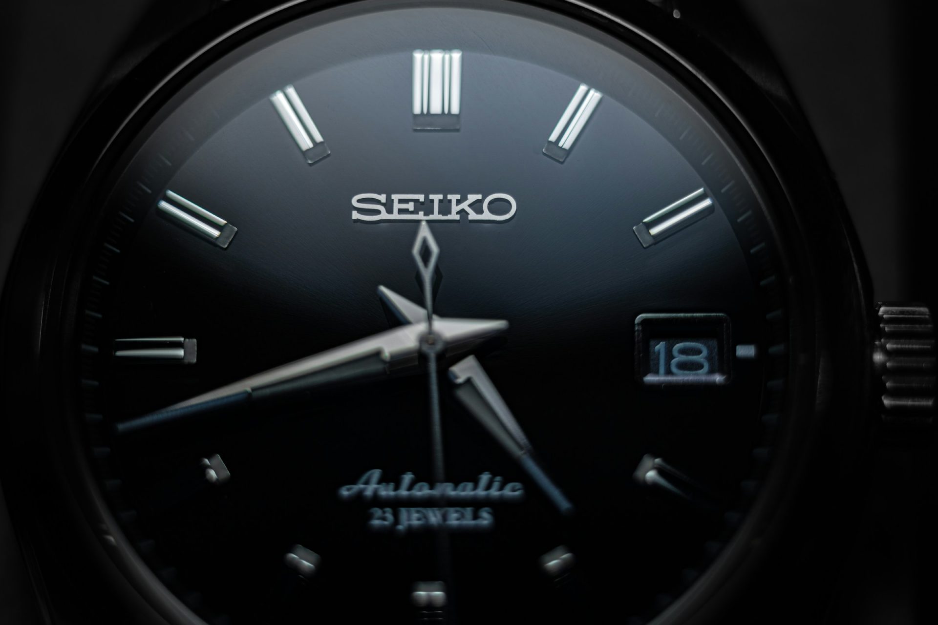 Close-up of a black-dial automatic watch with polished steel hands